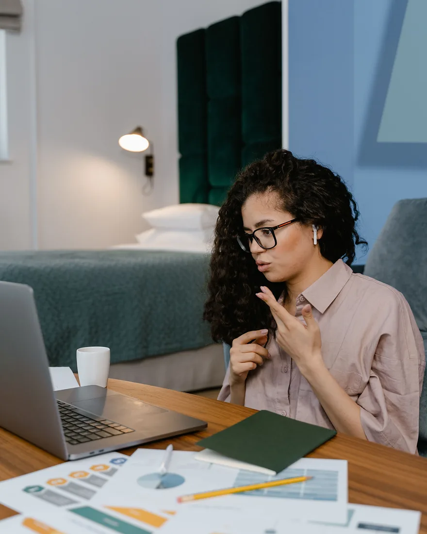 A founder on a video call, explaining again, her printed charts spread across the desk