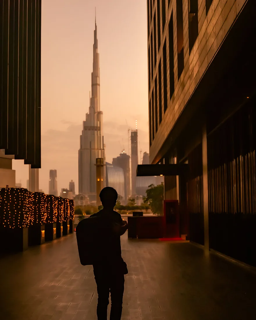 A founder newly arrived in Dubai, walking toward Burj Khalifa at dusk
